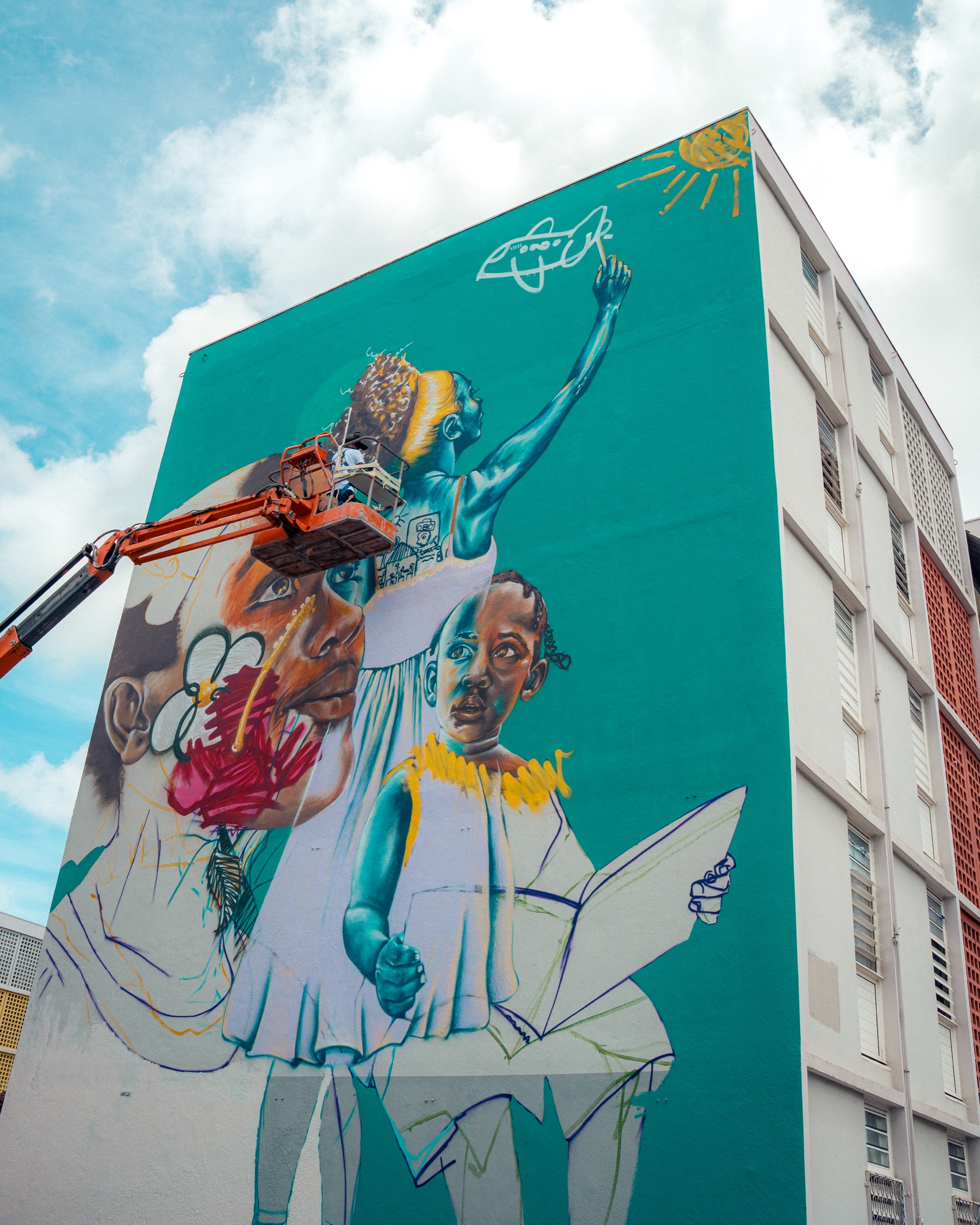 Fresque turquoise représentant plusieurs générations devant un immeuble
