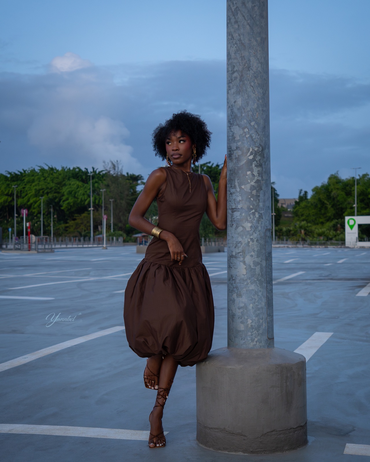 Xyo pose dans une robe brune au milieu des lignes d’un parking