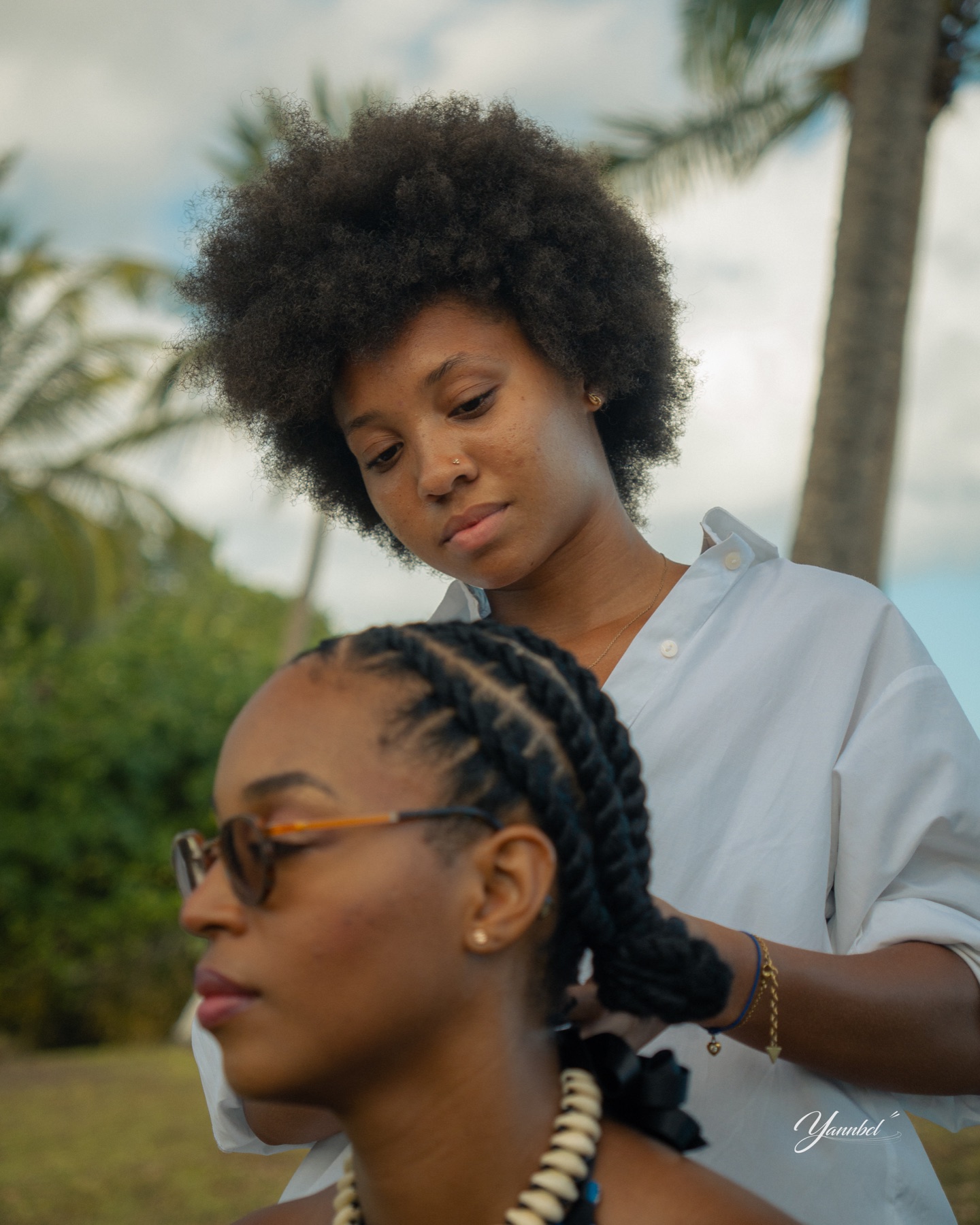 La coiffeuse réalise les tresses de Clara en extérieur