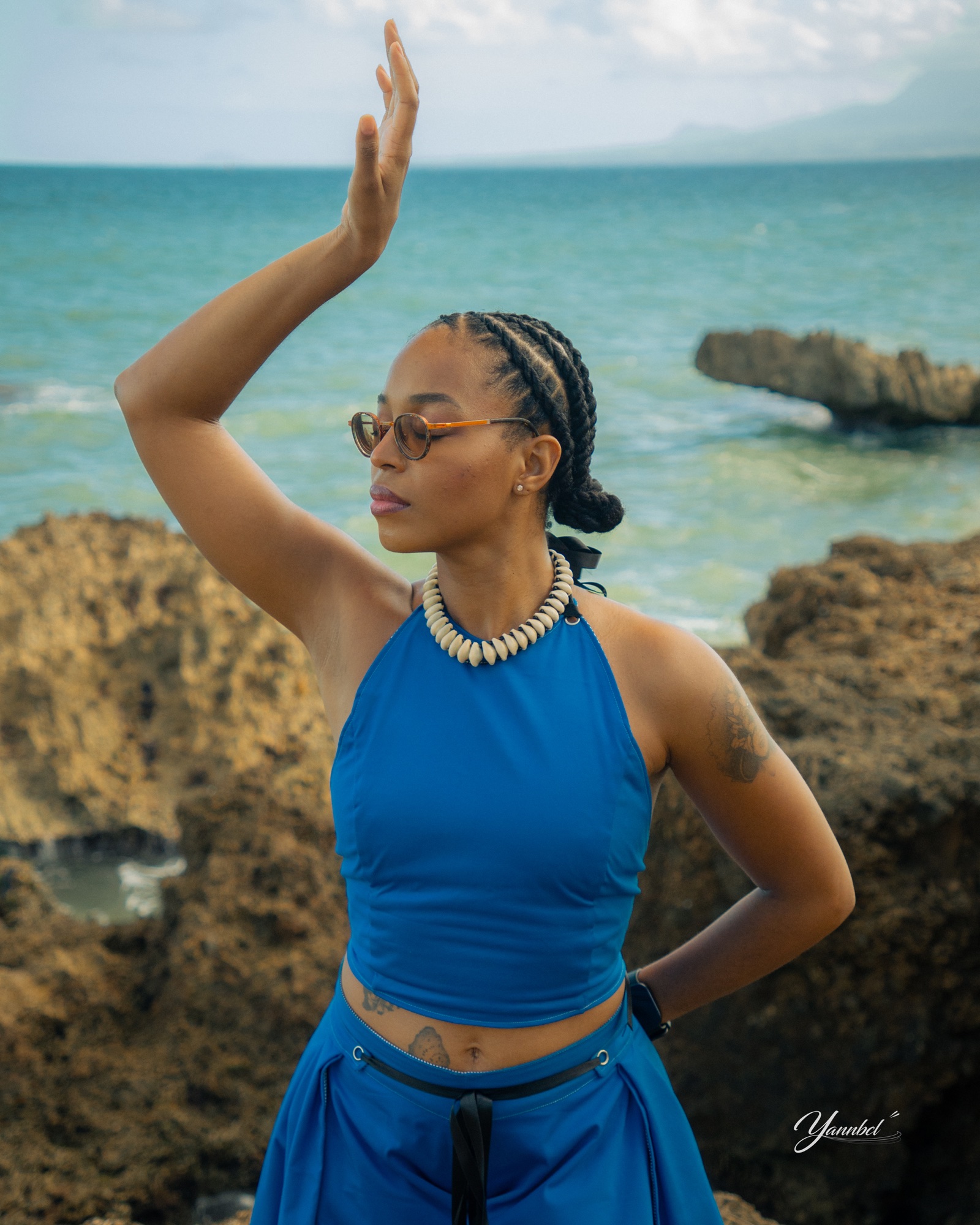 Portrait de Clara en tenue bleue face au littoral guadeloupéen